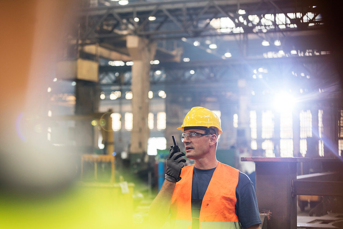 Steel worker using walkie-talkie in factory