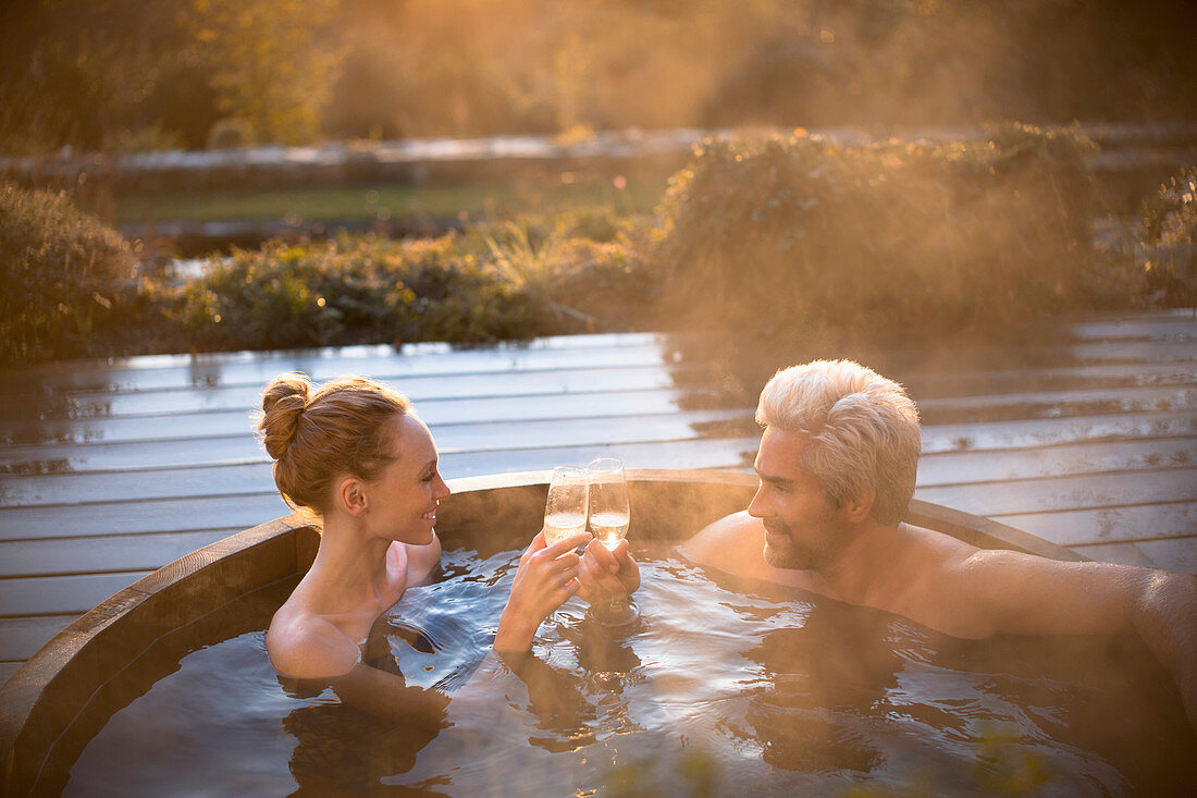 Couple toasting champagne glasses in hot tub