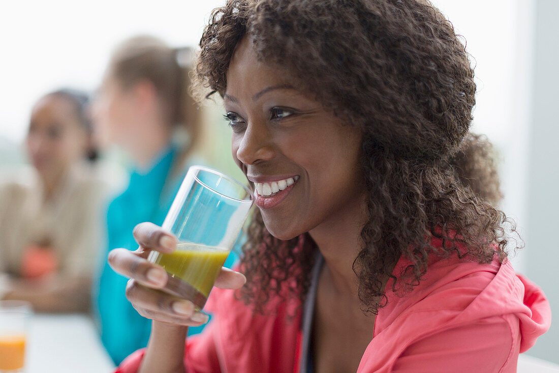 Smiling woman drinking healthy green smoothie