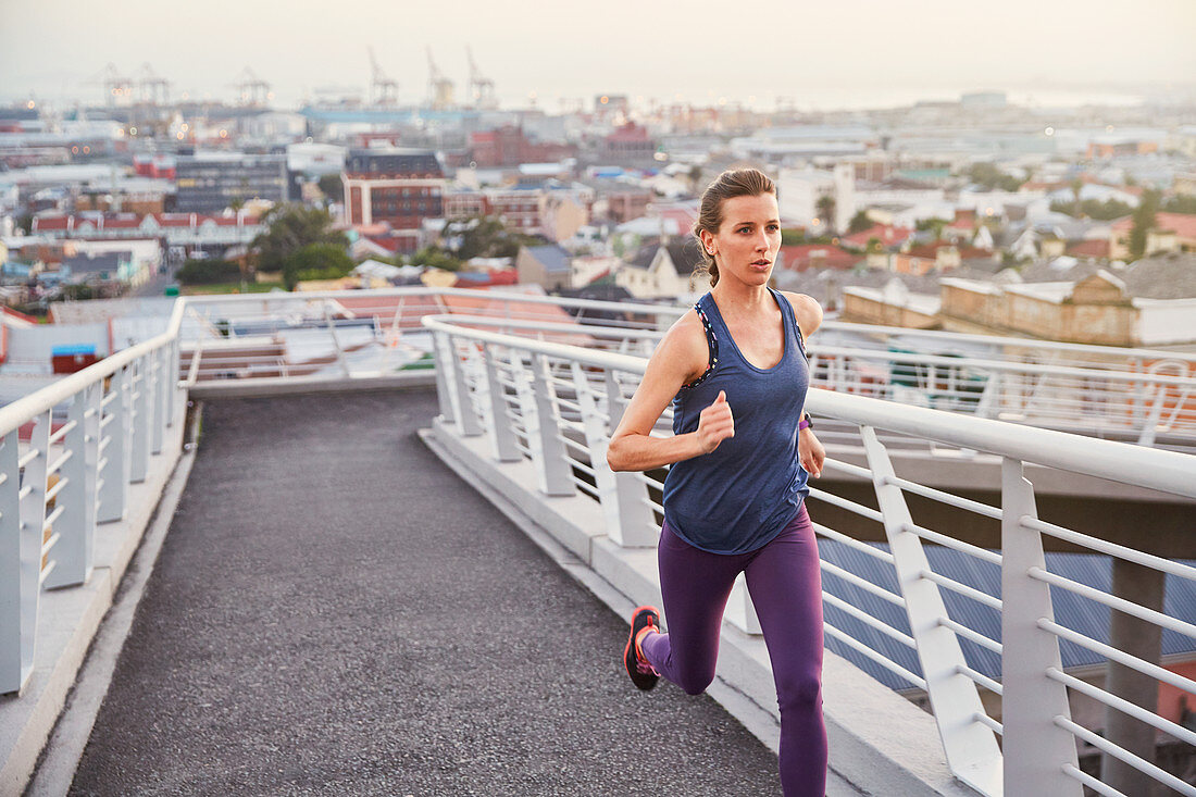 Female runner running on urban footbridge