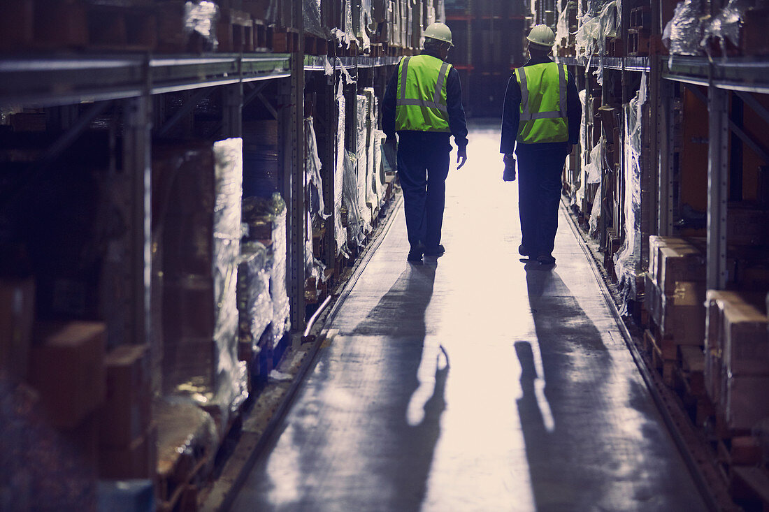 Workers walking in aisle of distribution warehouse