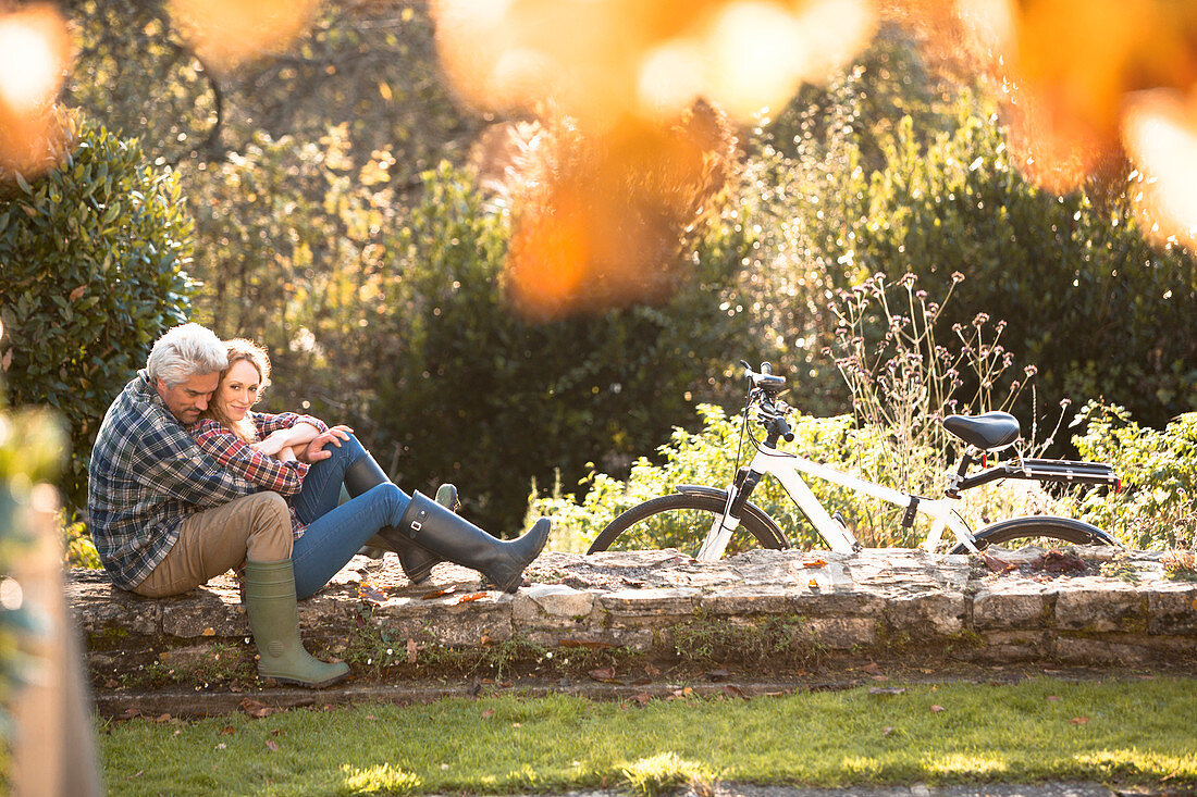 Couple hugging on stone wall in autumn park