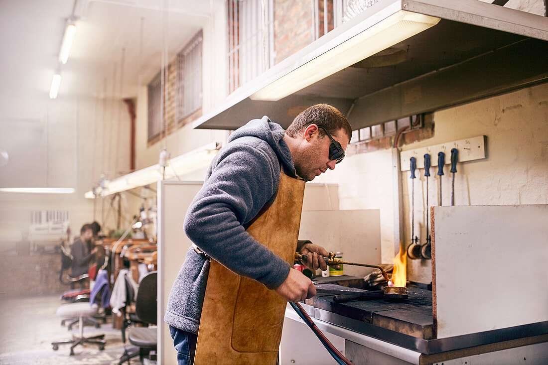 Jeweller using torch heating metal in workshop