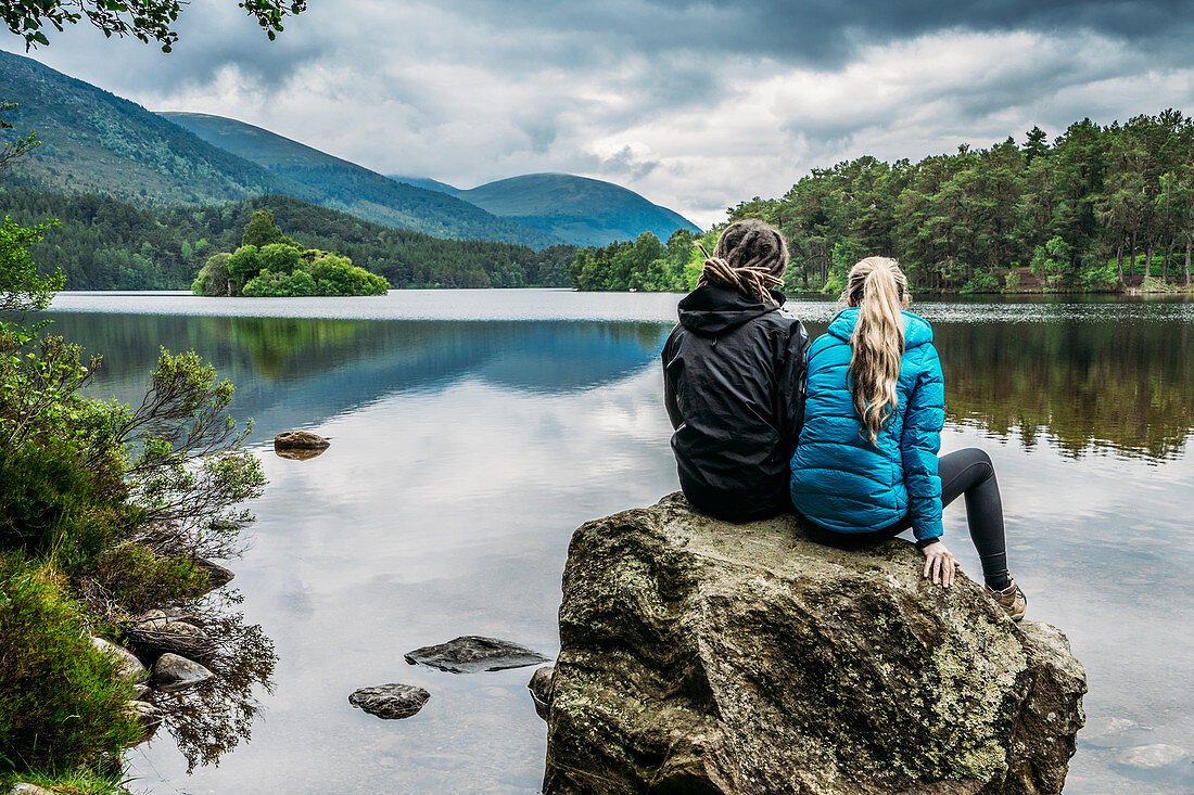 Couple sitting on rock, Loch an Eilein, Scotland
