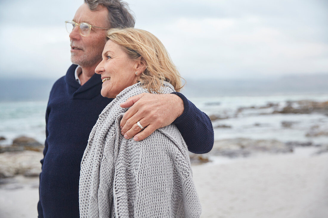 Affectionate senior couple hugging on winter beach