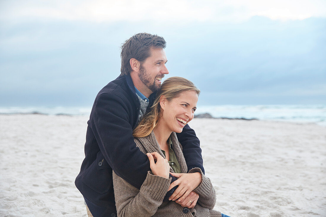 Happy couple hugging on winter beach