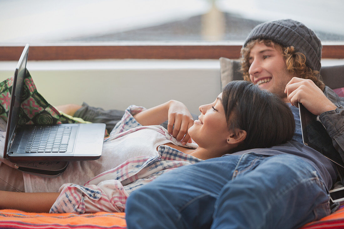 Young couple relaxing laying using laptop