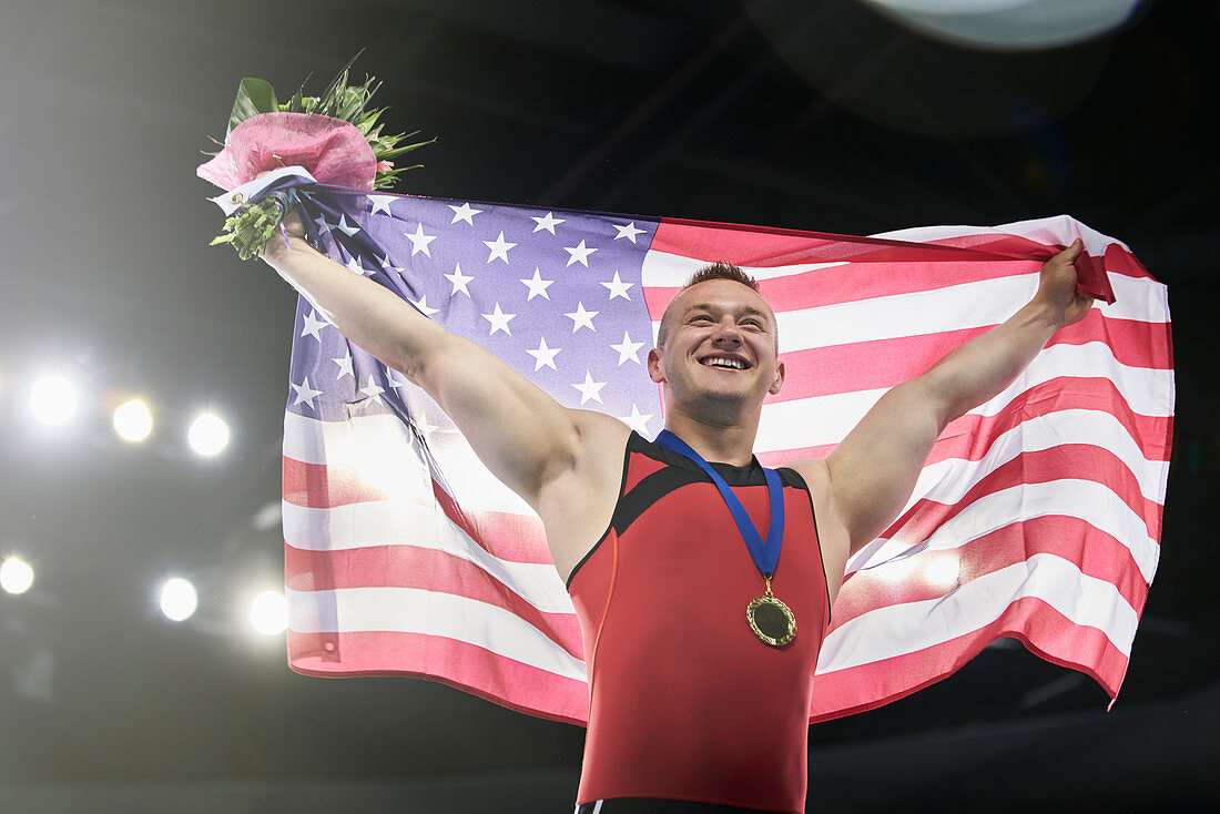 Male gymnast holding American flag on podium
