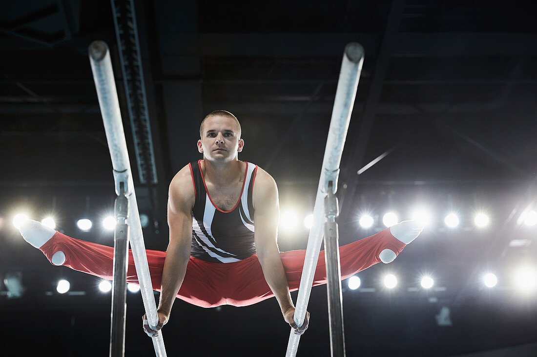 Male gymnast performing splits on parallel bars