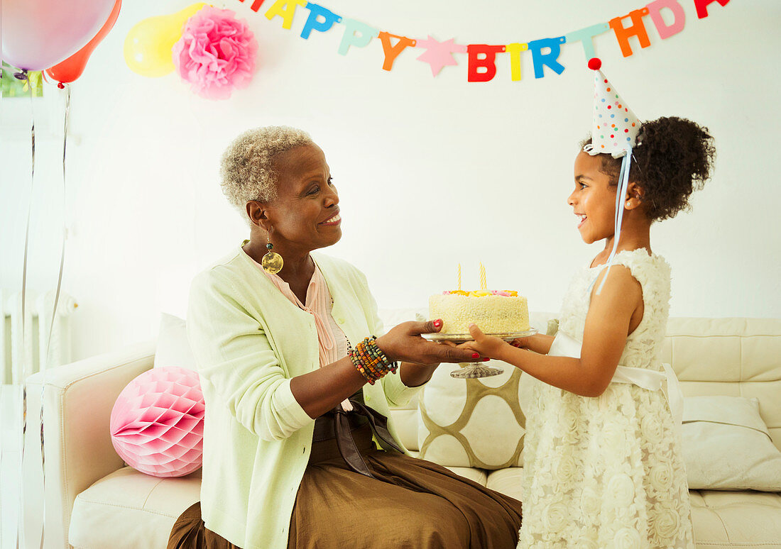 Grandmother and granddaughter holding cake