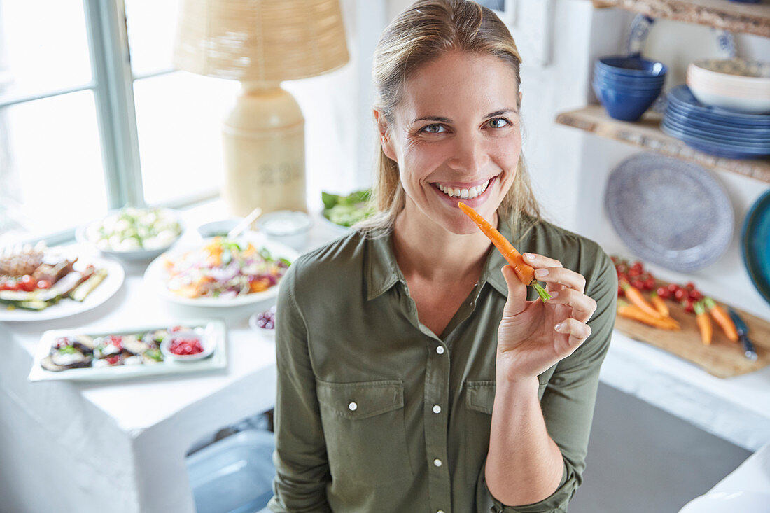 Portrait smiling woman eating carrot