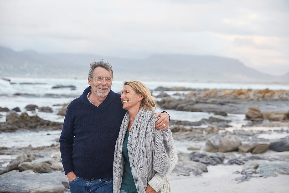 Smiling senior couple walking on winter beach