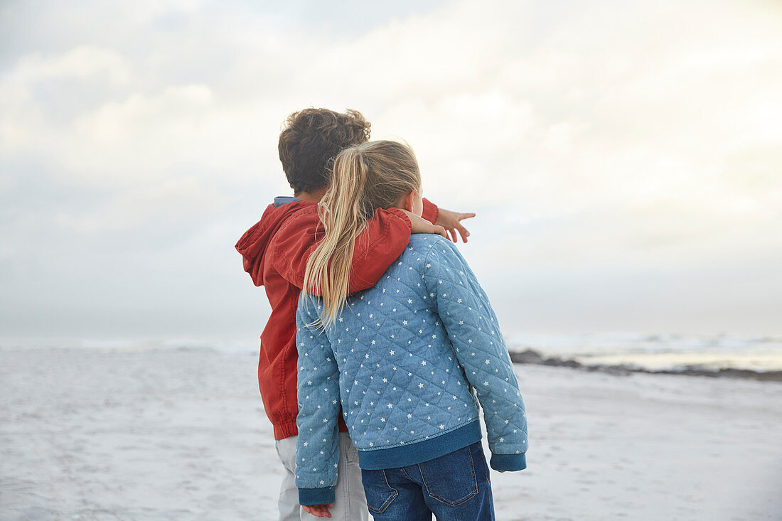 Brother and sister looking at winter ocean