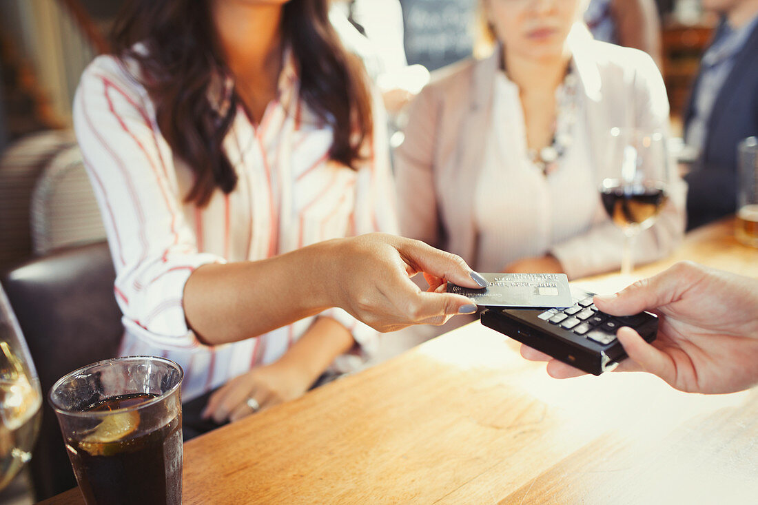 Woman paying bartender with contactless