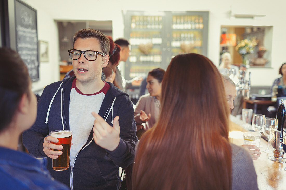 Man drinking beer and talking to woman at bar