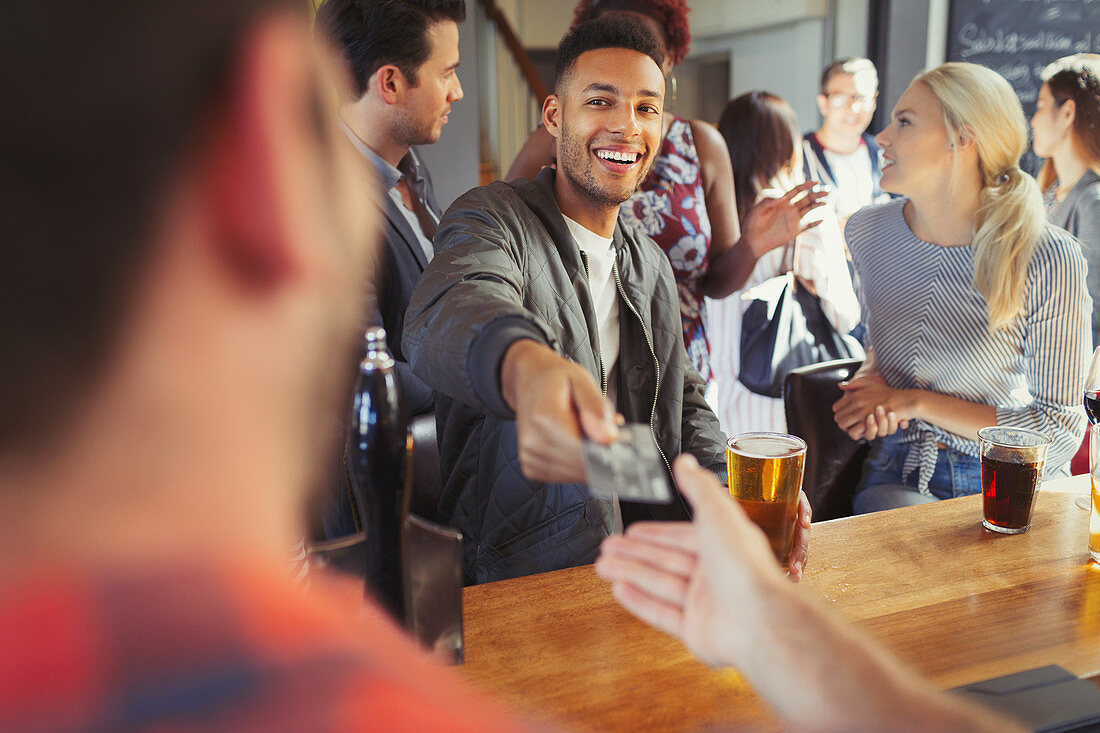 Man paying bartender with credit card at bar