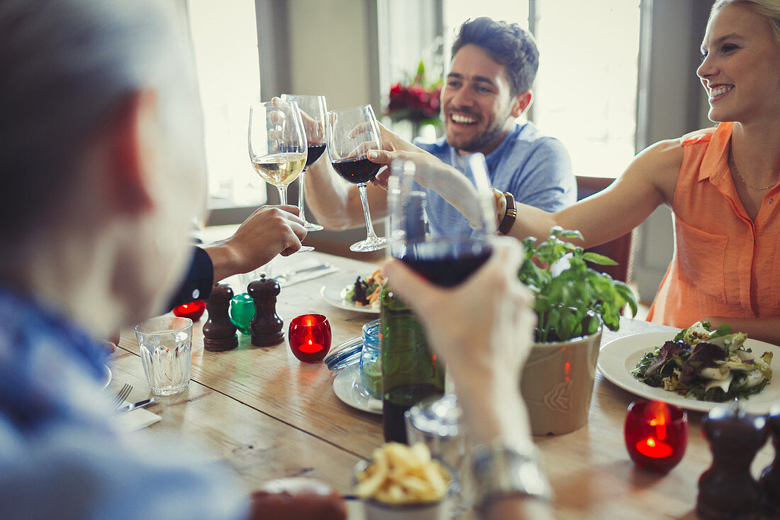 Smiling friends celebrating, toasting wine glasses