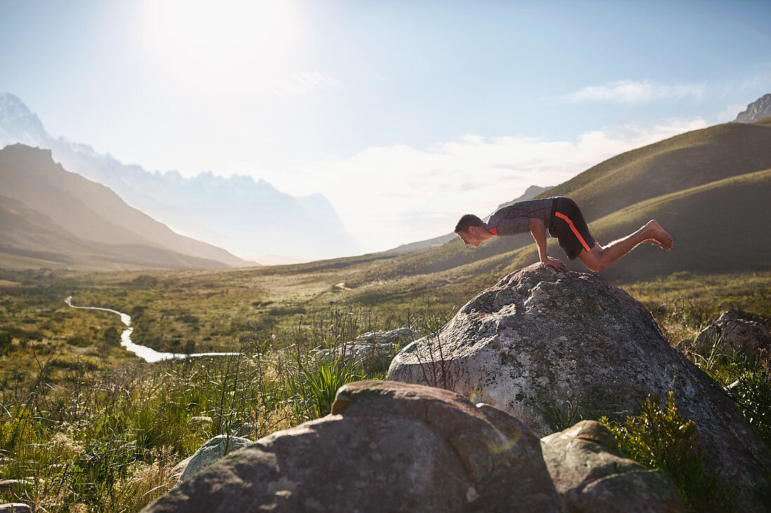 Young man balancing on hands on rock