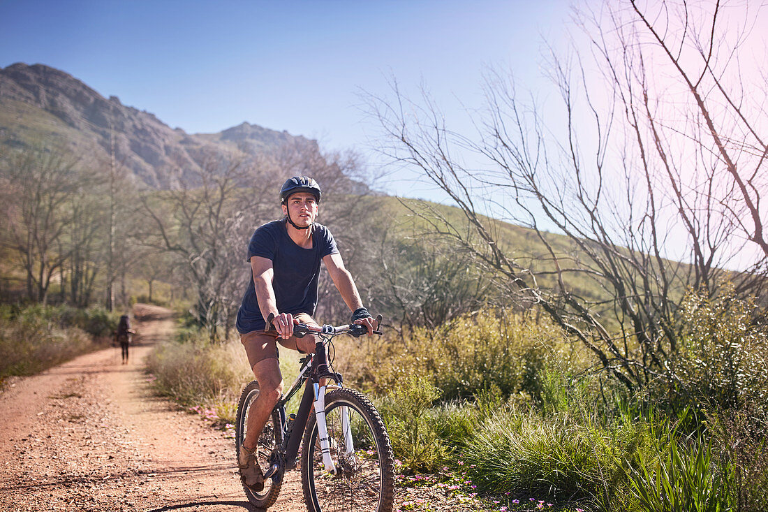 Young man mountain biking on, remote dirt road