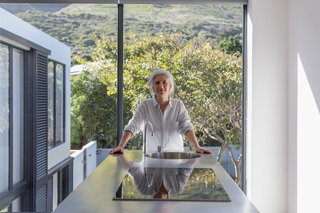 Portrait confident mature woman standing kitchen