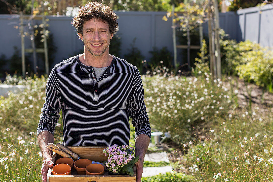 Portrait smiling man holding gardening tray