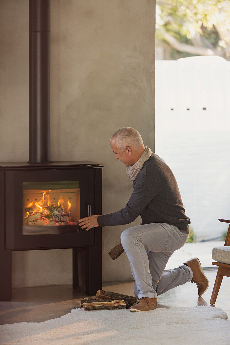 Man placing firewood in wood stove