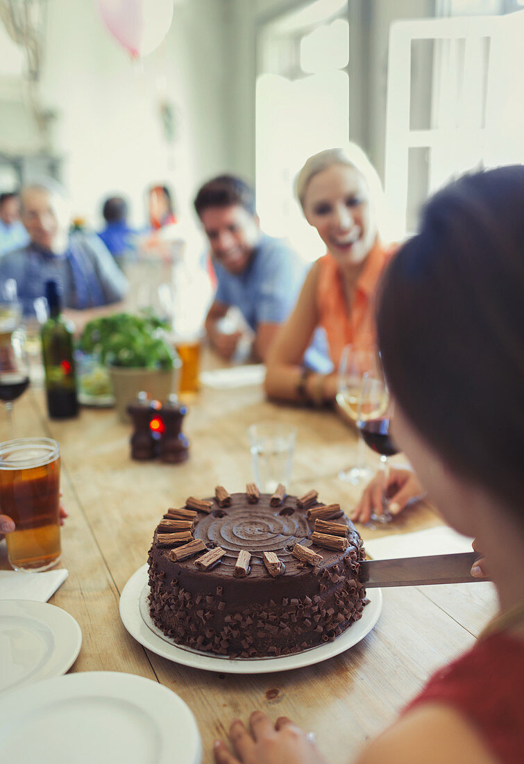 Woman cutting chocolate birthday cake with friends
