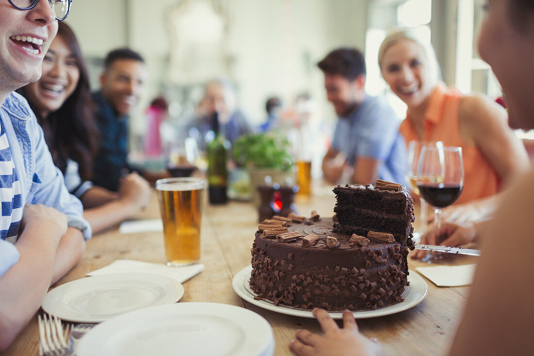 Woman serving chocolate birthday cake to friends