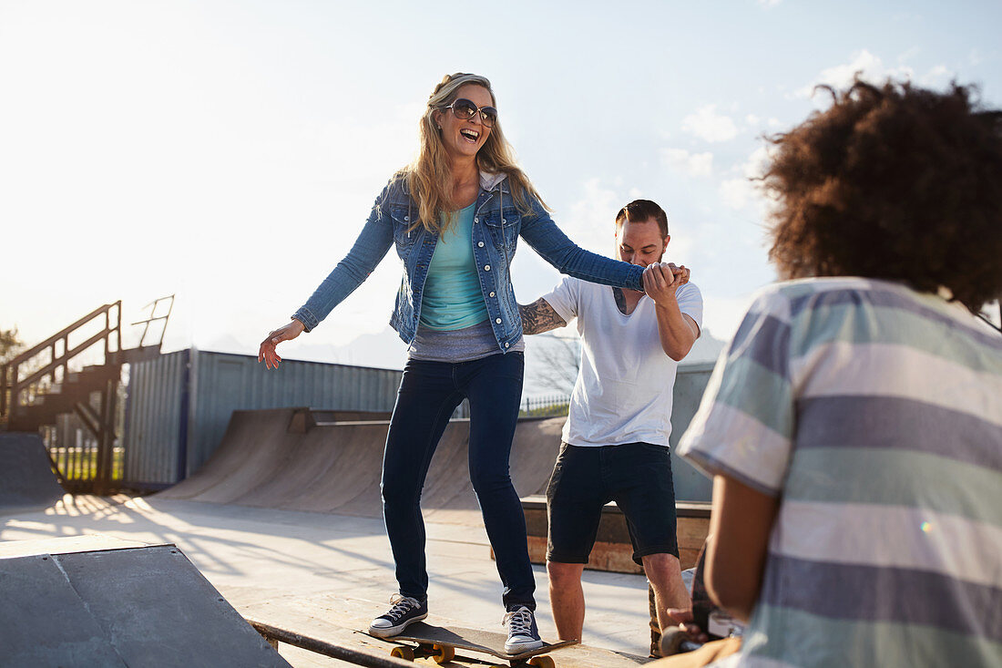 Boyfriend helping girlfriend on skateboard