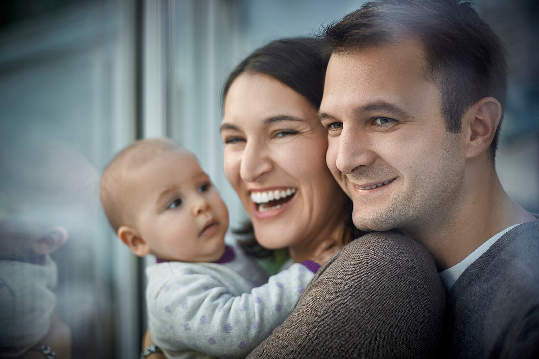 Smiling happy parents holding baby daughter