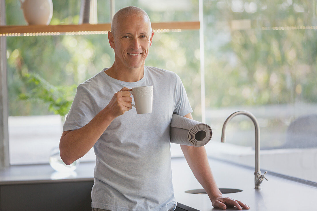 Portrait mature man with yoga mat drinking coffee