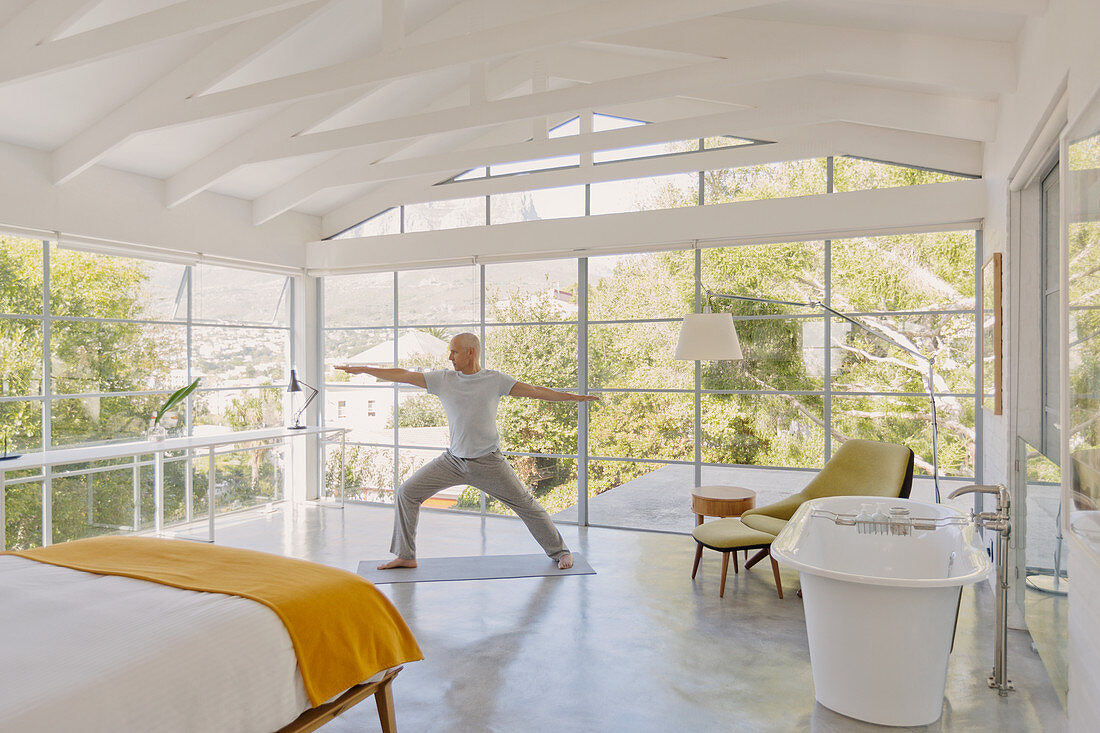 Mature man practicing yoga pose in bedroom