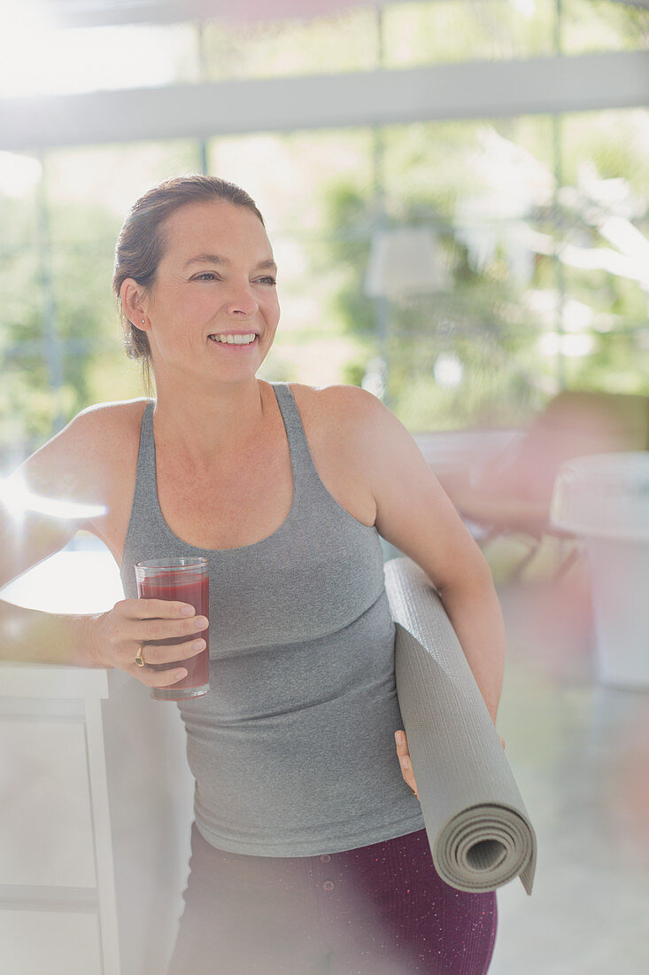 Woman with yoga mat drinking smoothie
