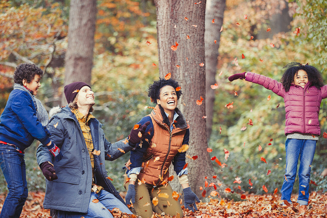 Playful young family throwing autumn leaves