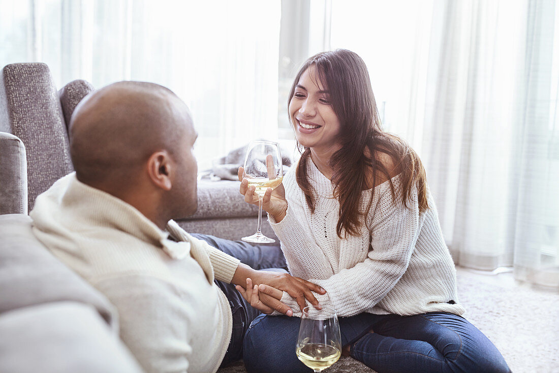 Smiling couple drinking white wine in living room