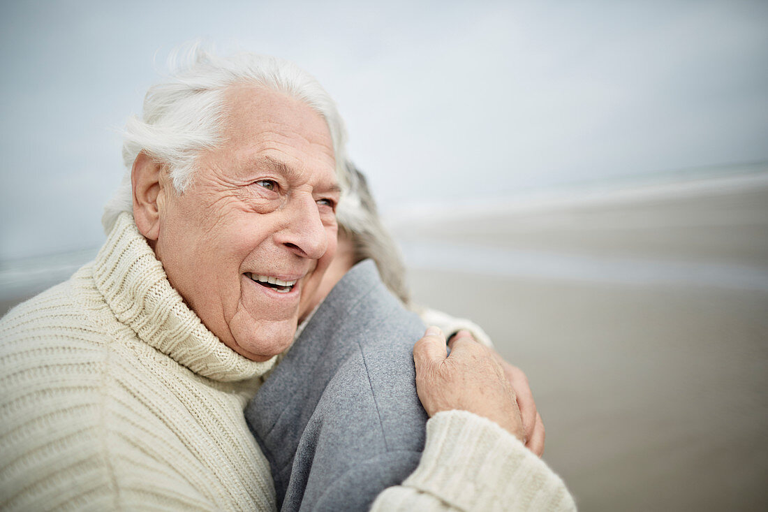 Affectionate senior couple hugging on winter beach