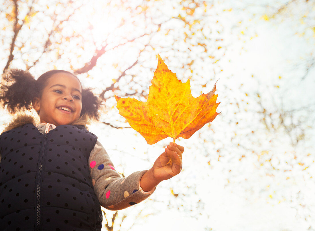 Smiling girl holding orange maple leaf