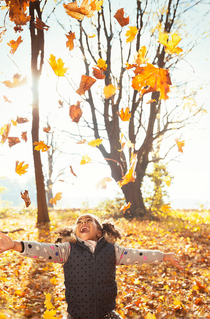 Playful girl throwing leaves overhead
