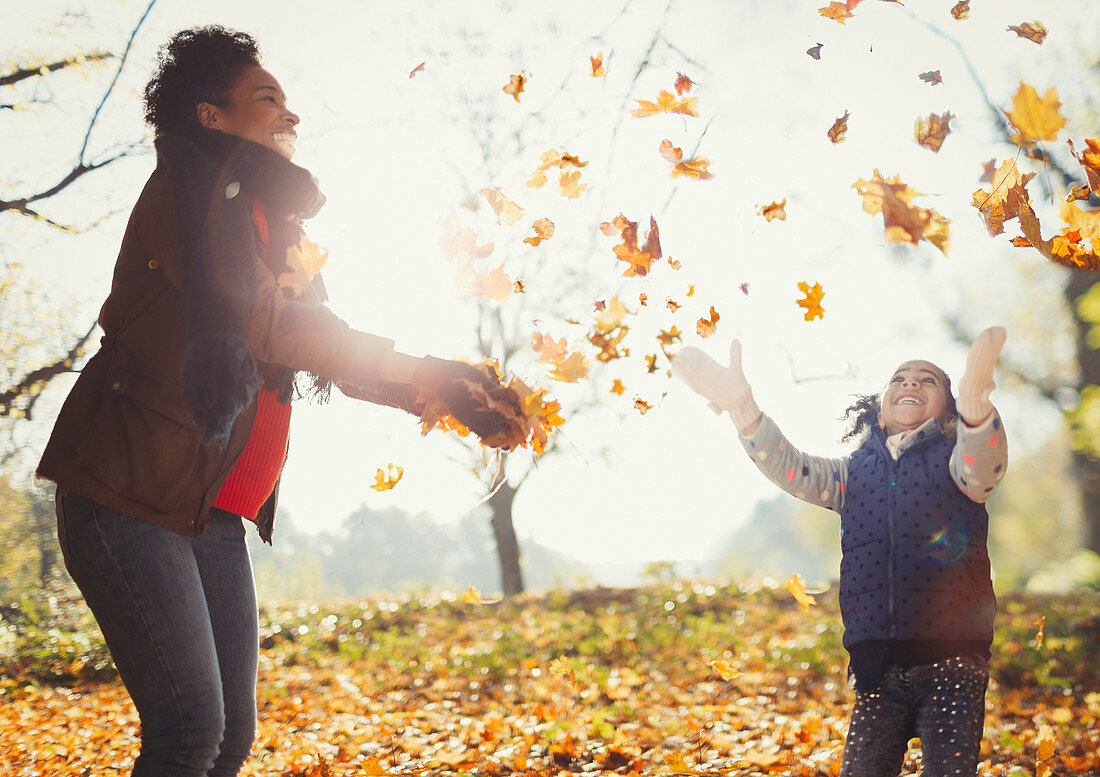 Playful mother and daughter throwing leaves