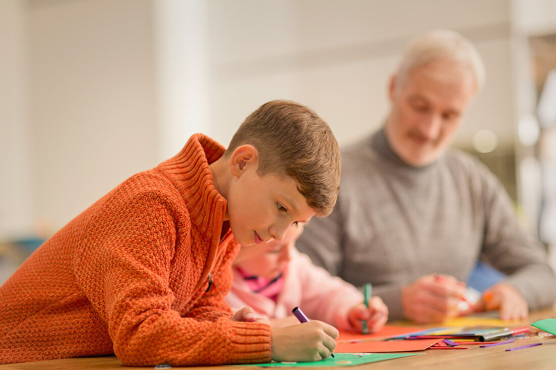 Boy drawing, doing crafts with family at table