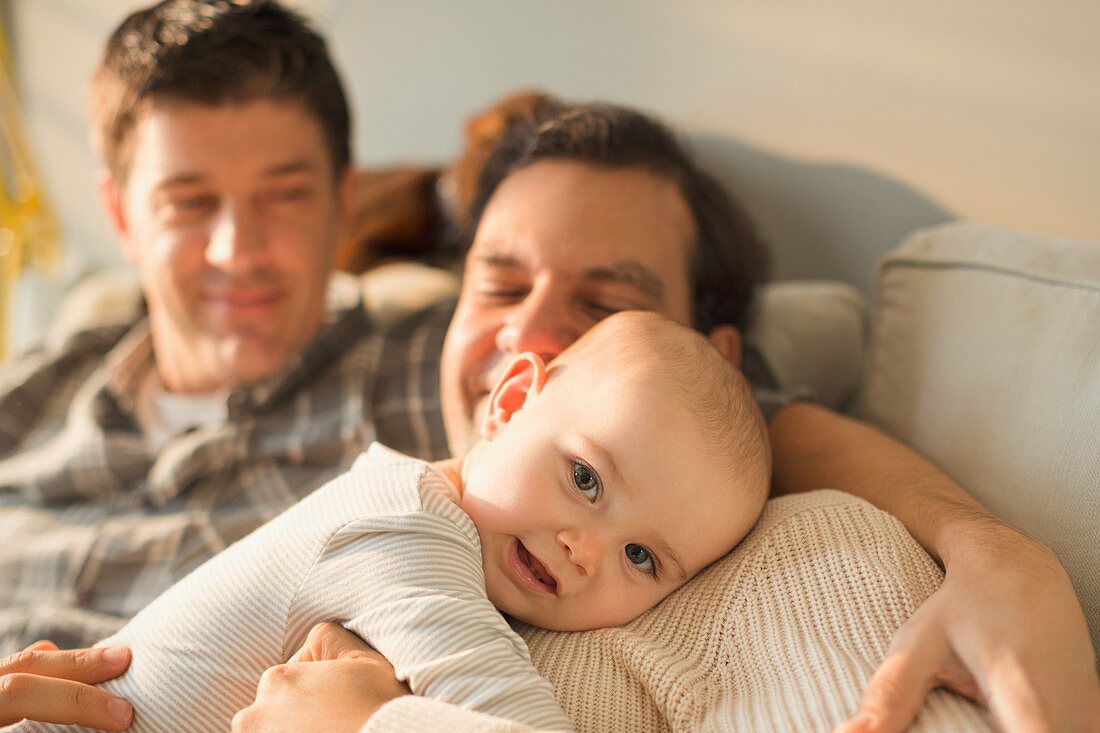 Portrait baby son cuddling with male gay parents