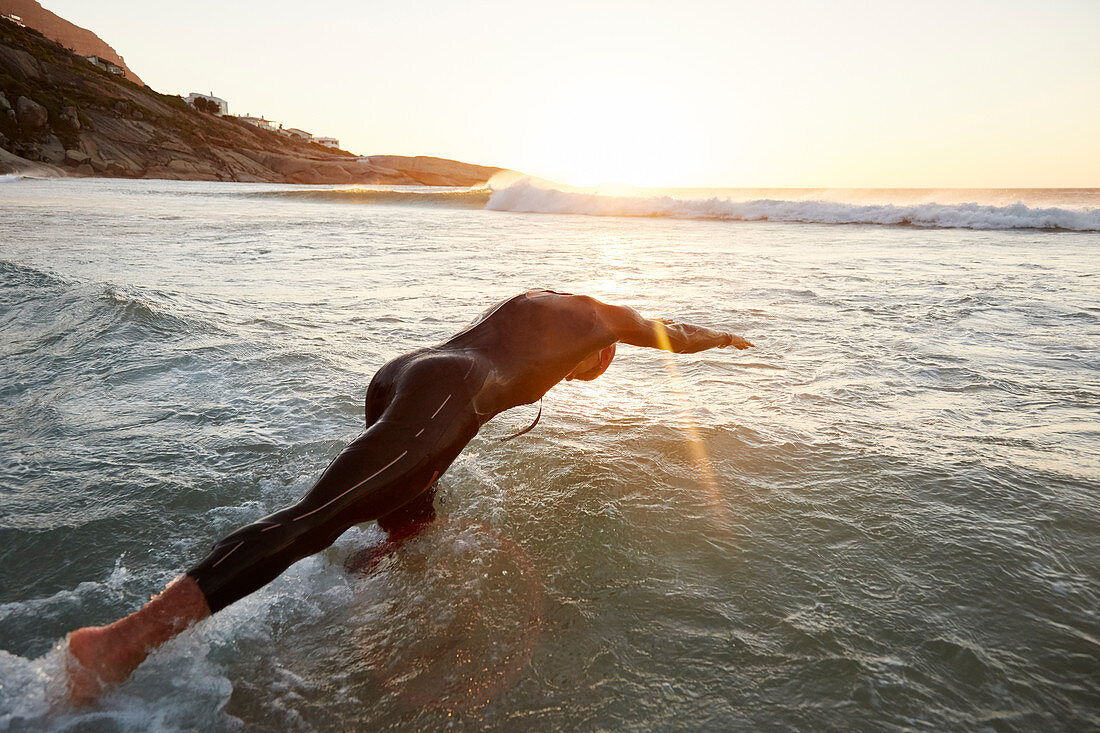 Male triathlete swimmer diving into ocean