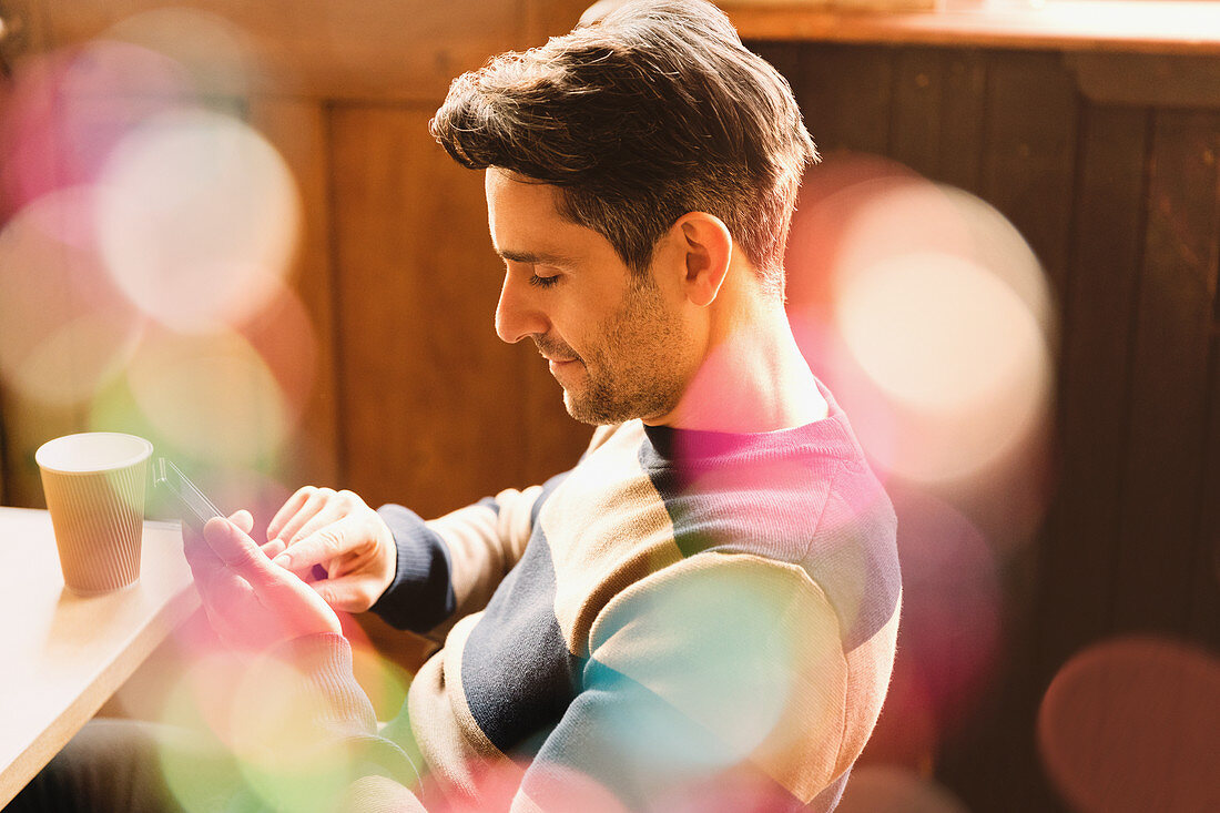 Man using cell phone and drinking coffee