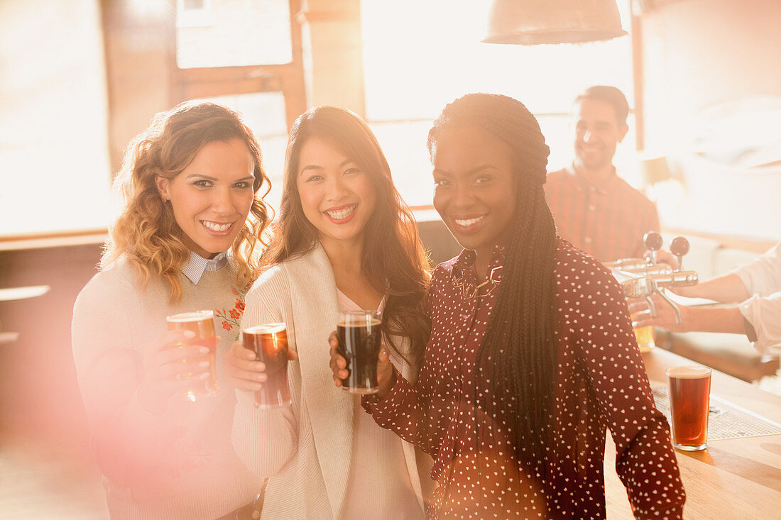 Portrait women friends drinking beer in bar