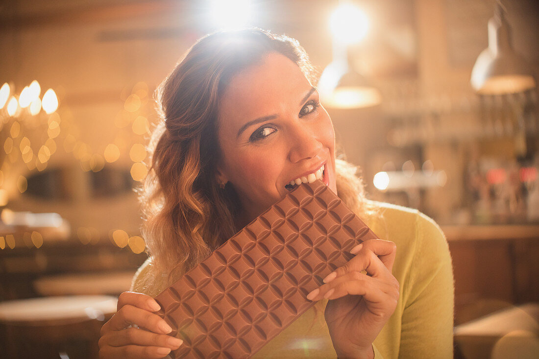 Woman biting into large chocolate bar