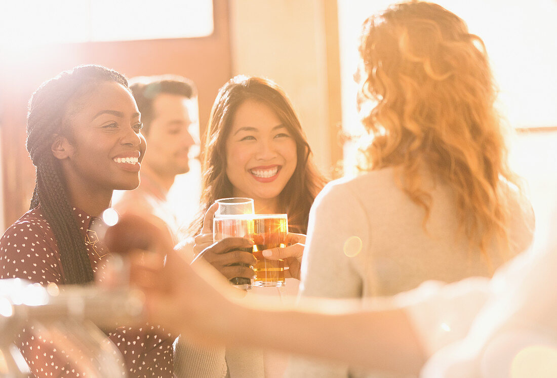 Smiling women friends toasting beer glasses