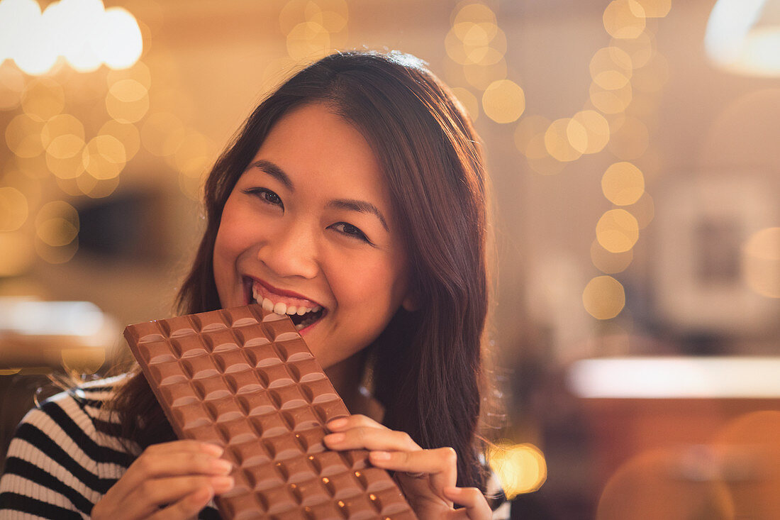 Chinese woman biting into large chocolate bar