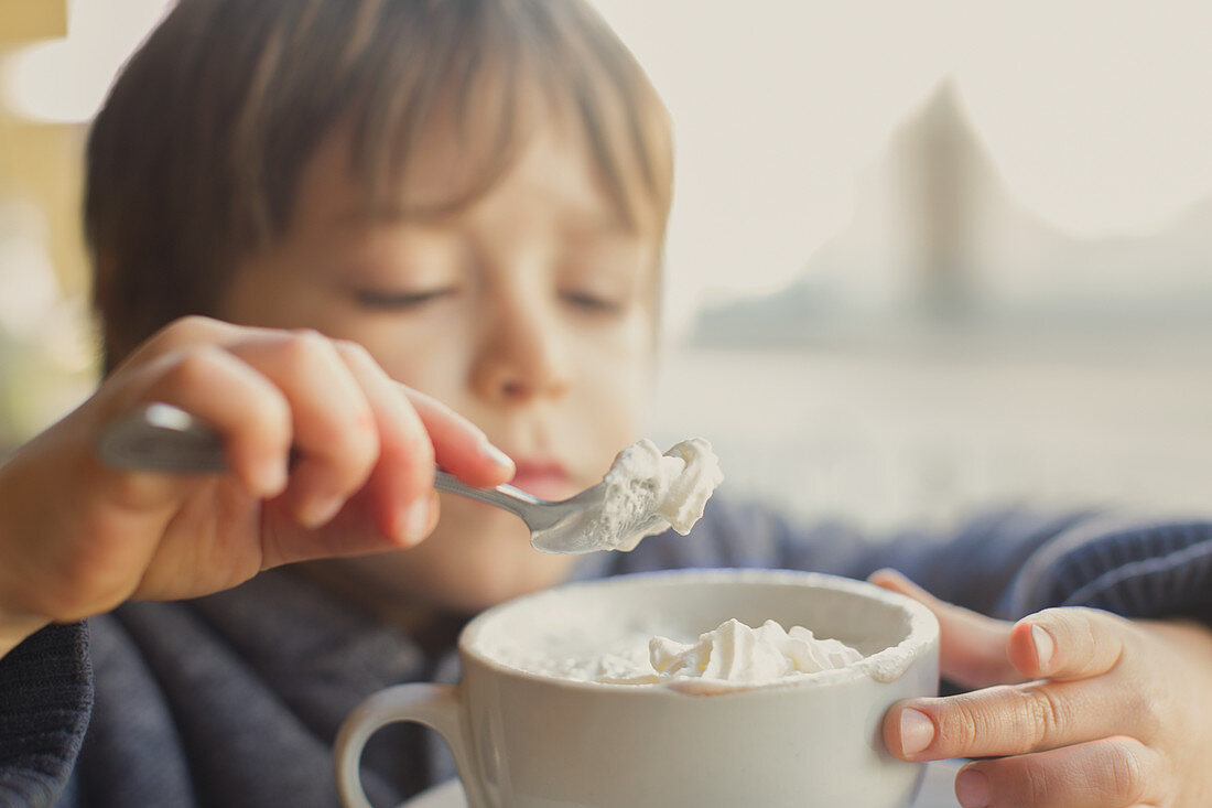 Boy eating whipped cream off hot cocoa