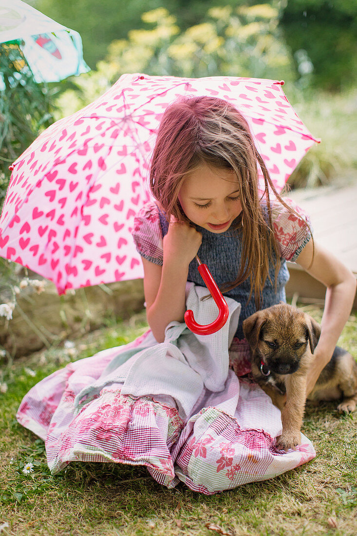 Girl with puppy dog holding umbrella