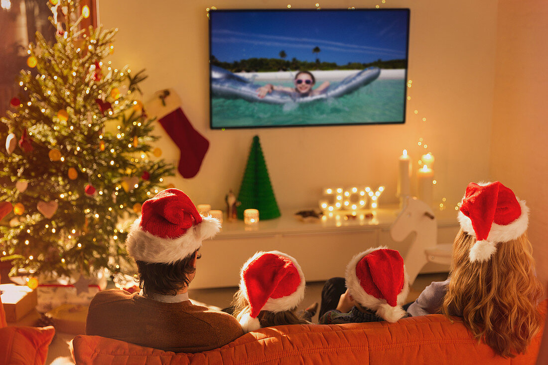 Family in Santa hats watching TV